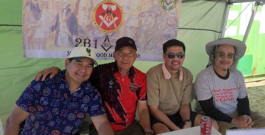 Four members sit together under an outdoor canopy beneath a banner with the lodge seal and the words 2B1ASK1.
